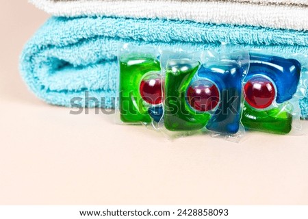 Laundry pods on beige background with soft towels, place for text.