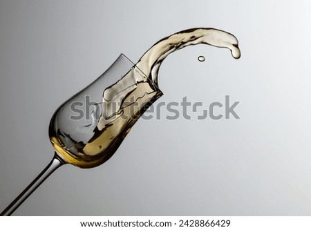 The drink spills out of the glass. Concept of the theme of premium alcohol. Copy space. Royalty-Free Stock Photo #2428866429