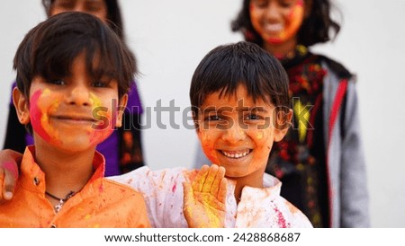Children covered in colored powder during the festival of Holi. Happy Cute Asian kids celebrate Indian holi festival with colorful paint powder on faces and body
