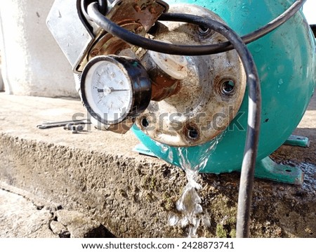 Water leakage from the green tank of the hydraulic pump. Do-it-yourself repair of an electric water pump. Maintenance of the water supply system of the house. Royalty-Free Stock Photo #2428873741