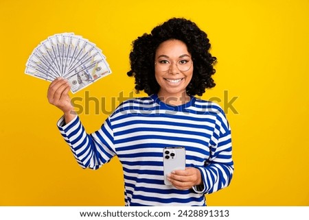 Photo of multiethnic multinational woman with chevelure in glasses hold dollars smartphone isolated on bright yellow color background Royalty-Free Stock Photo #2428891313