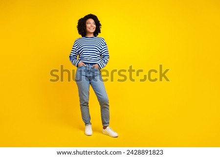 Full length photo of gorgeous girl wear striped pullover arms in pockets look at promo empty space isolated on yellow color background