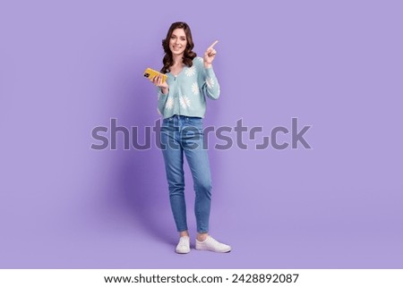 Full length photo of pretty positive woman wear flower print cardigan typing gadget pointing empty space isolated purple color background