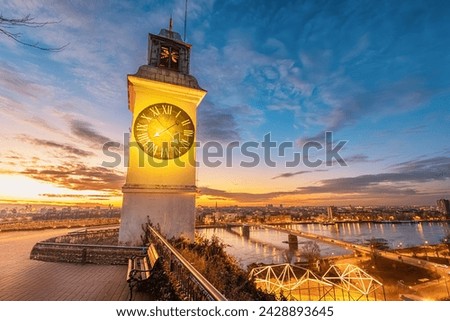 sun sets over Novi Sad, the iconic clock tower of Petrovaradin Fortress stands tall, offering a picturesque view of Serbian history and culture. Royalty-Free Stock Photo #2428893645