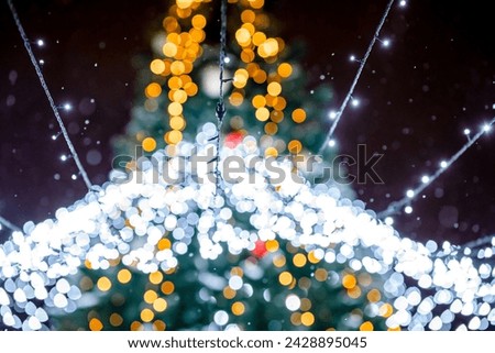 Colorful glowing garlands on the Christmas tree at night in a winter park, blurred background, specially defocus. Dark background for design.