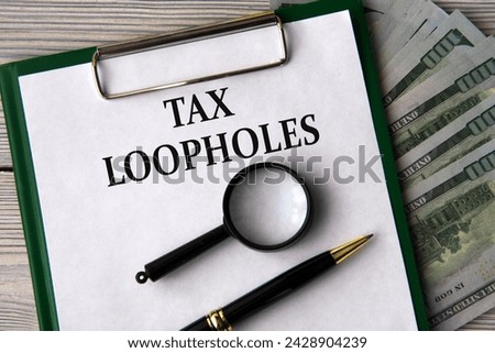 TAX LOOPHOLES - words on a white sheet on the background of banknotes, magnifying glass and pen Royalty-Free Stock Photo #2428904239