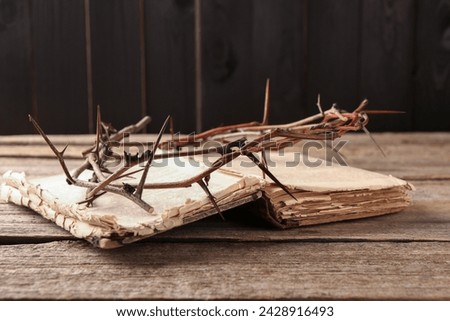 Crown of thorns and Bible on wooden table, closeup