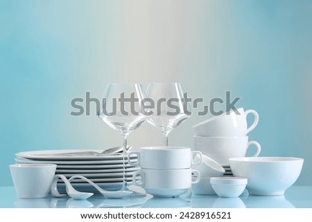 Set of many clean dishware and glasses on light blue table