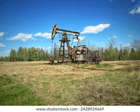 An old oil pump jack amidst greenery under daylight