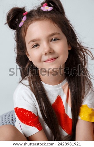 Close-up portrait of cute smiling little kid girl in white t-shirt on white studio background. Summer fashion kid