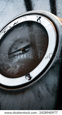 This is a picture of a grill thermometer, with rain drops all over it, giving it a foggy look and a nice aesthetic.