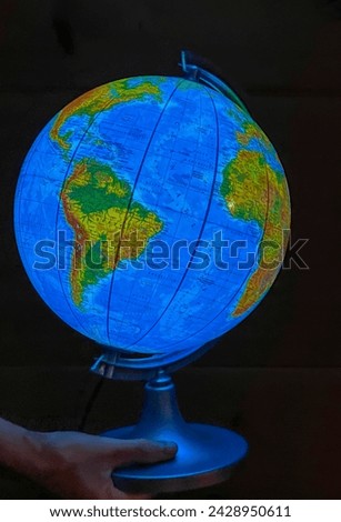 A child curious about the world holds an illuminated globe in his hands.