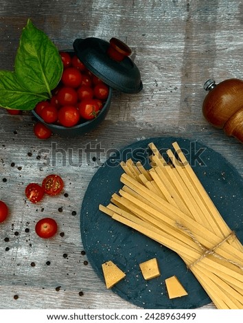 Food photography, on a table are placed cherry tomatoes with spaghetti ready for preparation with olive oil, pepper, basil and parmesan cheese, delicious on the palate.