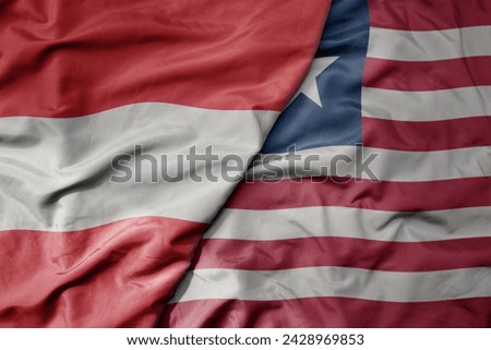 big waving national colorful flag of liberia and national flag of austria . macro
