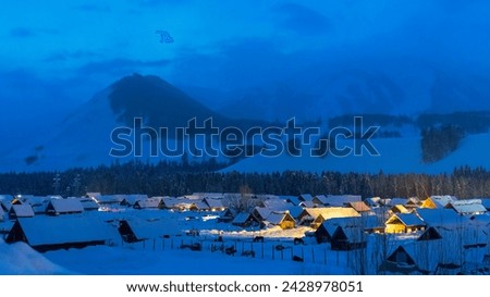Village under snowy mountains at night