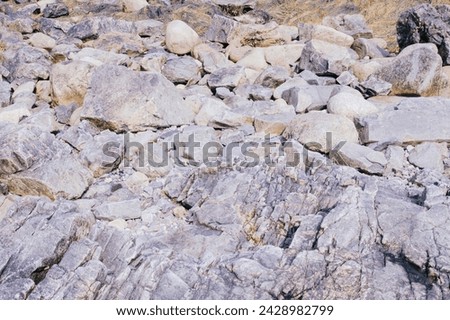 Washed-out seawall of rocks near the water line in Maine. Intentionally over-exposed for a grungy effect. Royalty-Free Stock Photo #2428982799