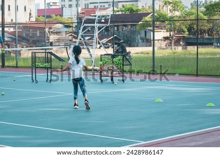 a young child girl playing tennis and practicing on a tennis court. Sports photography.
