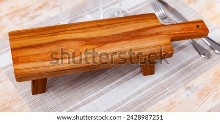 Closeup of empty natural wooden board for serving variety of breakfast items. Kitchen utensils for decorative and functional purposes Royalty-Free Stock Photo #2428987251
