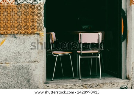 A terrace of an outdoor summer Spanish cafe. Table for two with chairs. Mosaic wall of an old house. European architecture details. Urban street photo