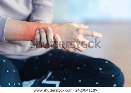 Woman with wrist pain or arm pain from heavy use on blurred background. Royalty-Free Stock Photo #2429041189