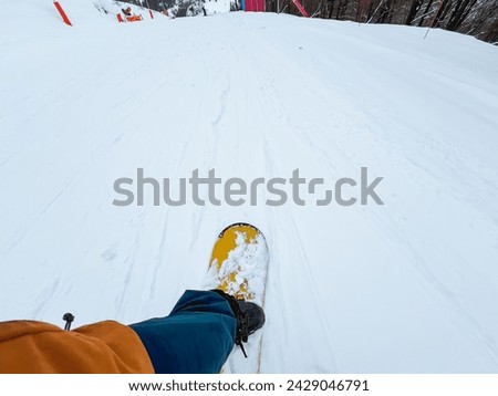 A Snowboarder Journey Through the Snowy Mountains. Snowboarder view of the slope and the mountains covered with snow. The sky is white and cloudy, creating a peaceful mood.