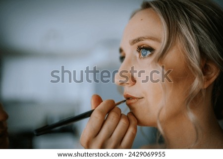 Riga, Latvia - January 20, 2024 -a close-up of a woman having makeup applied to her lips with a brush