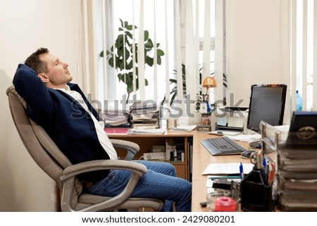 Calm millennial man in glasses sit relax at home office workplace take nap or daydream. Happy relaxed Caucasian young male rest in chair distracted from computer work, relieve negative emotions. Royalty-Free Stock Photo #2429080201
