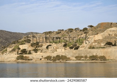 The abandoned Bastion Fortress and ruins of the famous historical landmark, Spinalonga, former Leper Colony on Kalydon, a rocky, arid Islet in the Bay of Elounda and wider area Mirabello Bay in Crete. Royalty-Free Stock Photo #2429080587