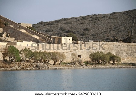 The abandoned Bastion Fortress and ruins of the famous historical landmark, Spinalonga, former Leper Colony on Kalydon, a rocky, arid Islet in the Bay of Elounda and wider area Mirabello Bay in Crete. Royalty-Free Stock Photo #2429080613