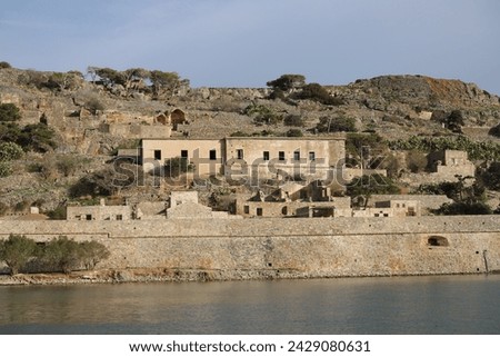 The abandoned Bastion Fortress and ruins of the famous historical landmark, Spinalonga, former Leper Colony on Kalydon, a rocky, arid Islet in the Bay of Elounda and wider area Mirabello Bay in Crete. Royalty-Free Stock Photo #2429080631