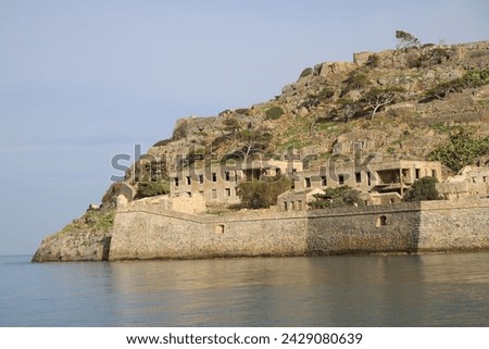 The abandoned Bastion Fortress and ruins of the famous historical landmark, Spinalonga, former Leper Colony on Kalydon, a rocky, arid Islet in the Bay of Elounda and wider area Mirabello Bay in Crete. Royalty-Free Stock Photo #2429080639