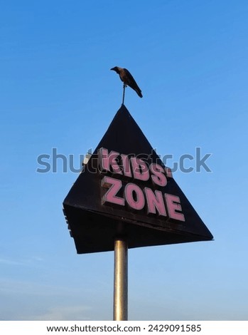 What makes this picture unique is the unexpected visitor perched on top of the sign: a crow. The bird is perfectly positioned as if it's part of the sign itself, and it looks quite content to be here