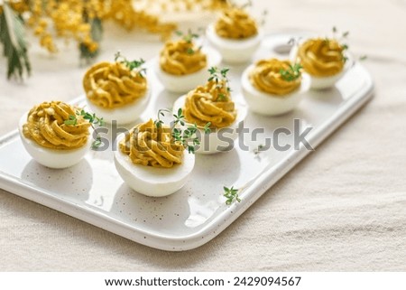 Easter breakfast idea. Stuffed easter eggs mimosa with egg yolk, turmeric, cream cheese and cress salad. Happy Easter traditional dish concept. Royalty-Free Stock Photo #2429094567