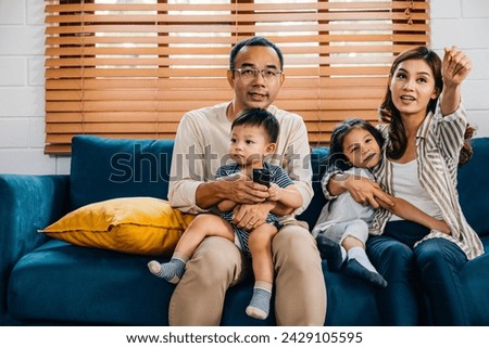 In the cozy living room a cheerful family with kids bonds over TV movies. The father mother son and daughter radiate joy and togetherness during their relaxation time.