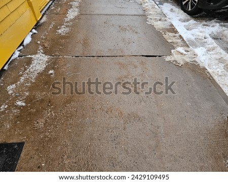 A top down view of a cleared sidewalk of snow with salt on it.