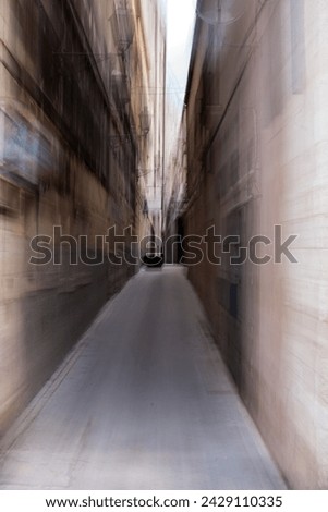 Long deserted narrow passage between two urban buildings with a concrete floor and diminishing perspective Royalty-Free Stock Photo #2429110335