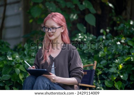 Cute pink hair girl drawing on digital tablet in garden, Woman Doing Freelance Work in Garden, woman with digital tablet with graffiti artwork.