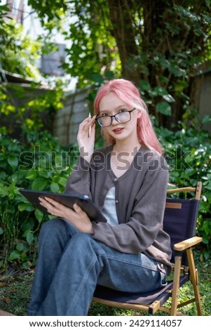 Cute pink hair girl drawing on digital tablet in garden, Woman Doing Freelance Work in Garden, woman with digital tablet with graffiti artwork.