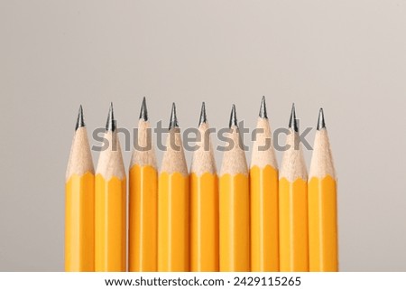 Many sharp graphite pencils on grey background, space for text. Macro view