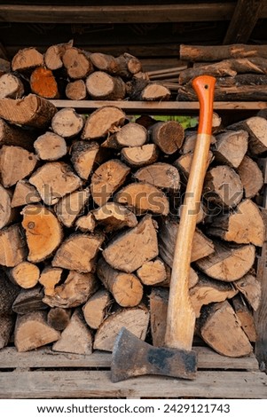 Axe in front of a stack of wood in a woodshed. Natural vertical background. High quality photo