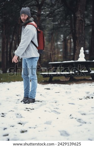 Young model playing with snow on the ground in a snowy forest in winter