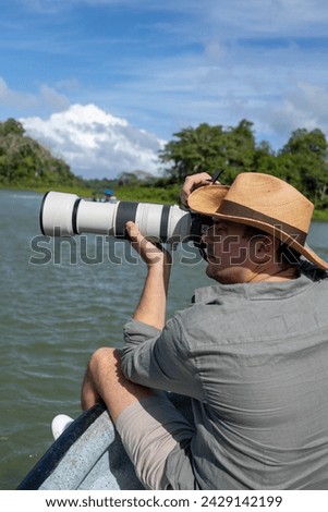 Photographer with telephoto lens with hat on a boat