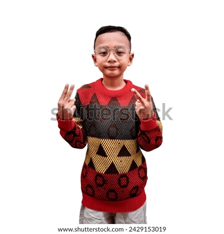 Portrait of happy handsome Asian boy smiling standing wearing sweater he is showing his fingers doing victory sign V or number two, looking at camera, isolated white background studio shot