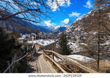 Pathway leading to a viewpoint above the village of Zermatt overlooked by the Matterhorn peak in the Swiss Alps in winter - Idyllic landscape with wooden chalets surrounded by snow capped mountains