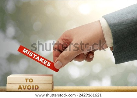Business hand put a stack of wooden blocks with 'mistakes to avoid' text on the table. Mistake concept Royalty-Free Stock Photo #2429161621