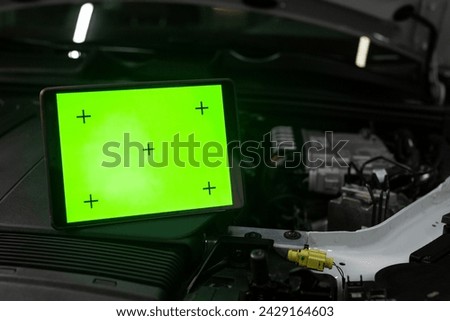 Car diagnostics. A computer with a green screen sits on top of a car engine. concept of a modern car equipped with a computer engine control system