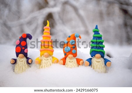 Figurines of colorful dwarfs made of plasticine. New Year decorations on a background of snow.