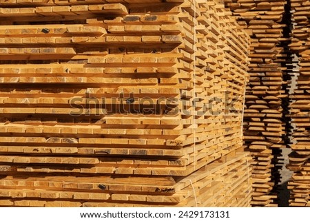 A stack of boards. The boards are stacked on the sawmill. Sawing boards on a sawmill. Production of wood material.