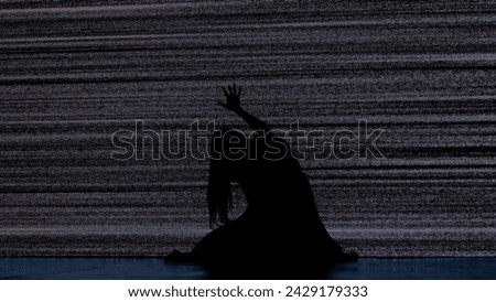 Silhouette against digital television screen. Thriller scene scared trapped woman silhouette sitting on the floor hitting big digital screen with noise.