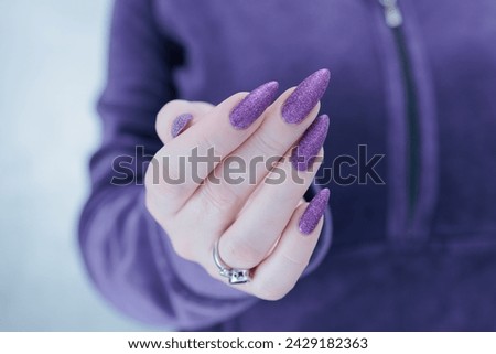 Female hands with long nails and purple manicure 